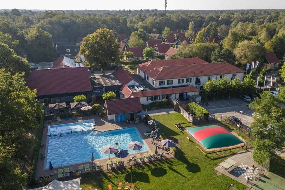 Aerial view of a holiday park with red-roofed houses and a swimming pool in the south of the Netherlands